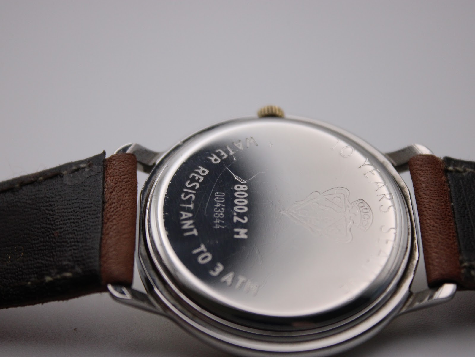 Close-up of the watch case back engraved with model 8000.2.M, serial number, and 'water resistant to 3 ATM'.