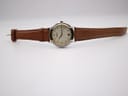 Close-up of the original Gucci-signed gold-tone buckle on the brown leather strap.