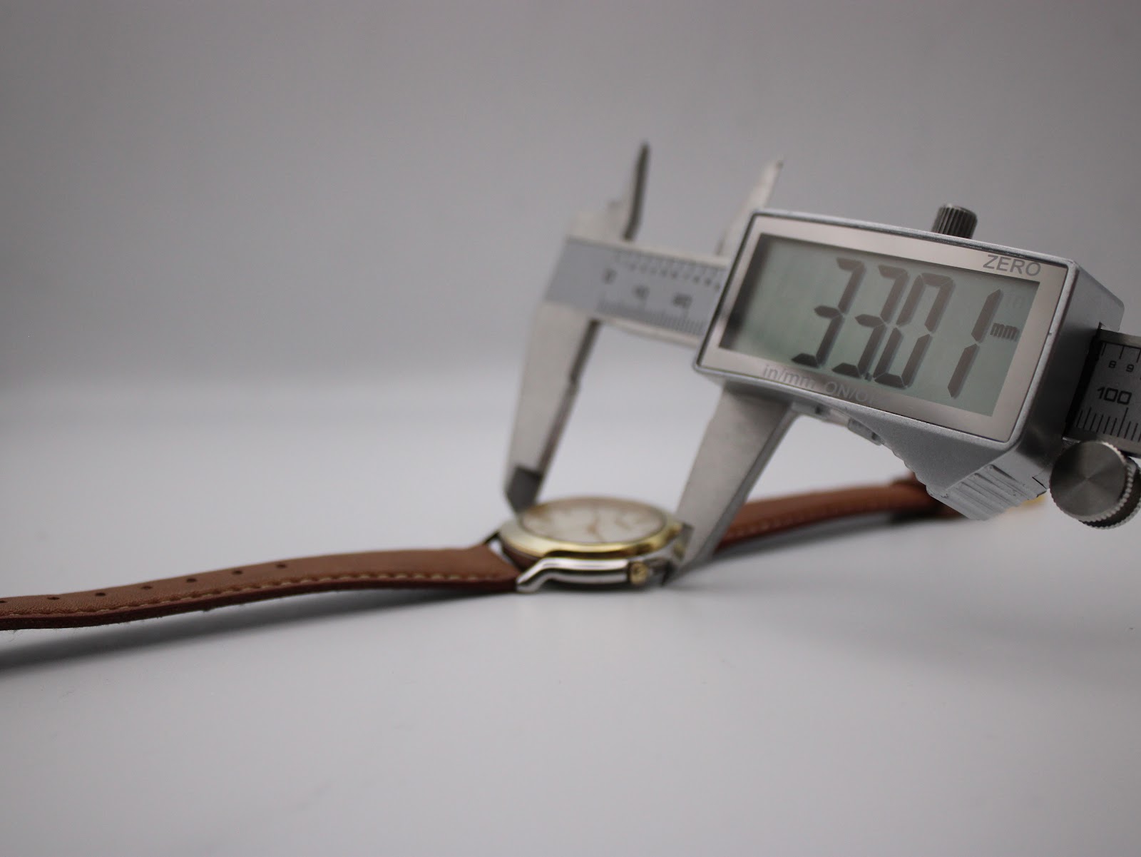 Digital caliper measuring the watch case diameter at 33.01 mm, showing the watch profile.