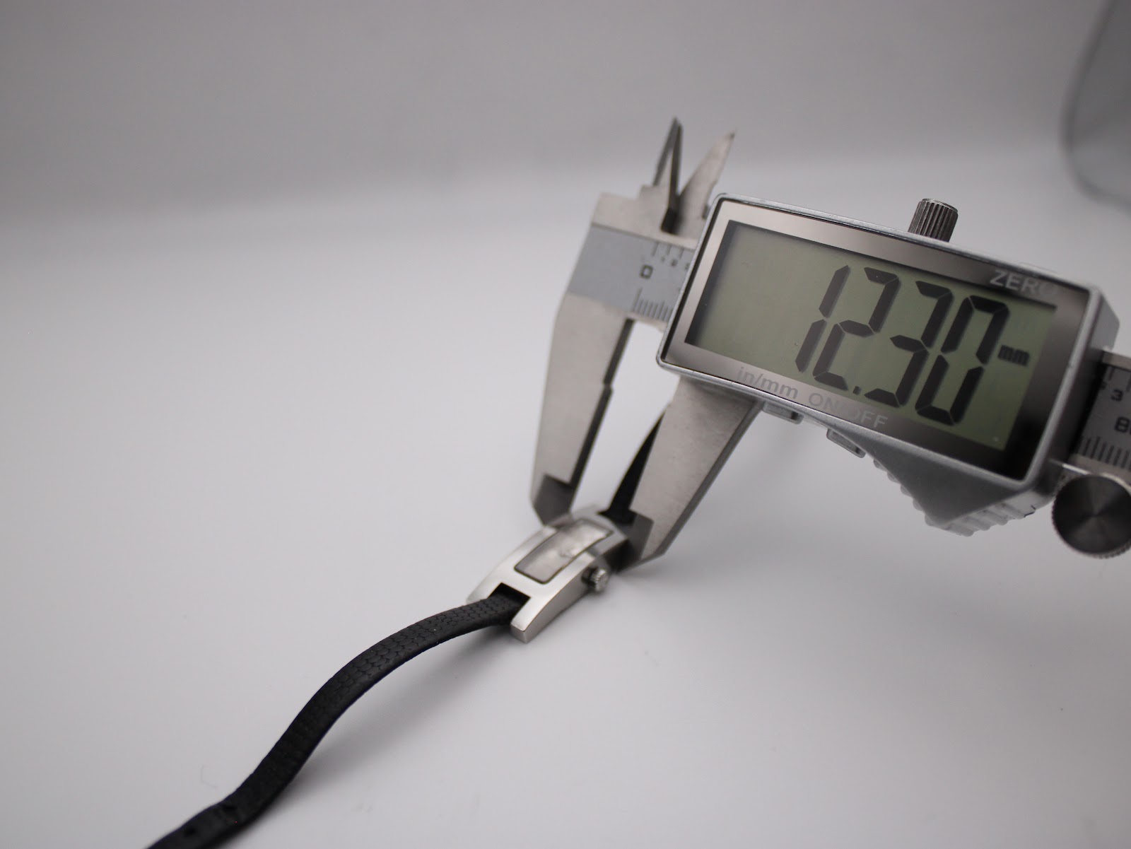 Digital caliper measuring the case width of the Gucci 3900L watch, precisely displaying 12.30mm.