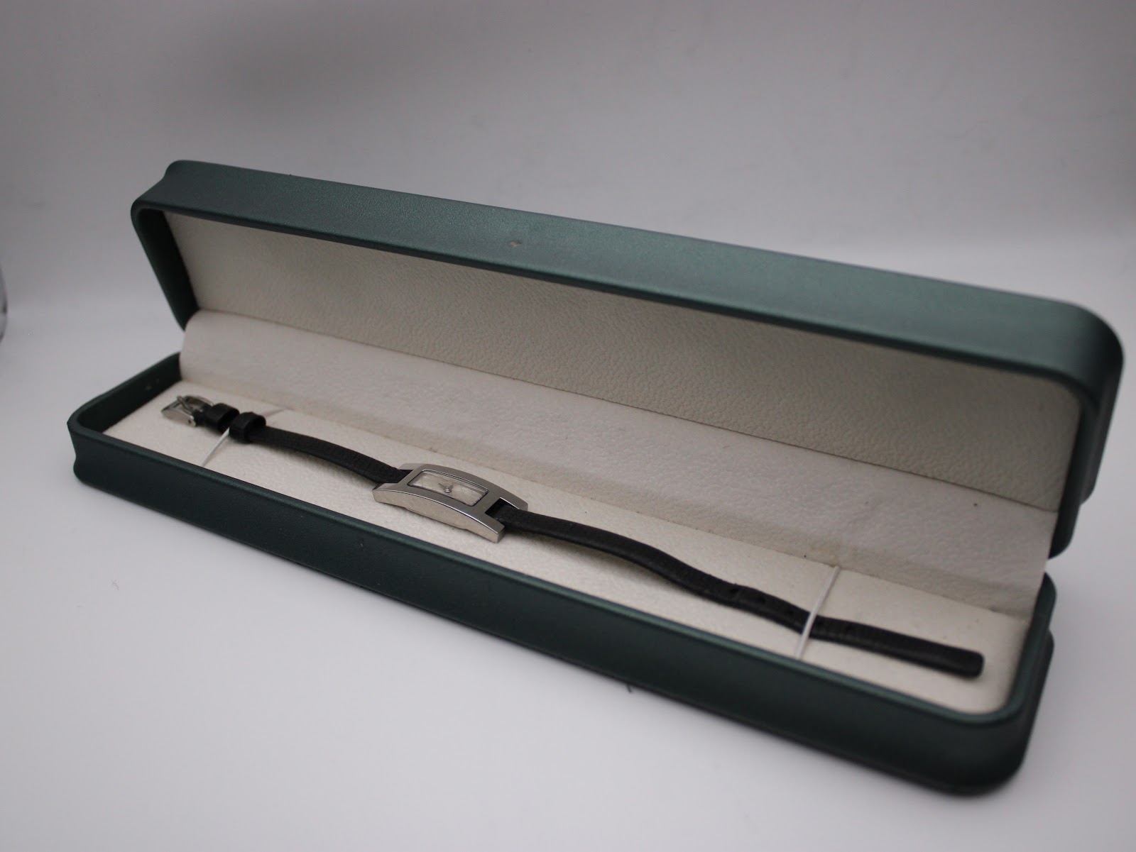 The Gucci 3900L watch presented inside a long, slim green watch box for display.