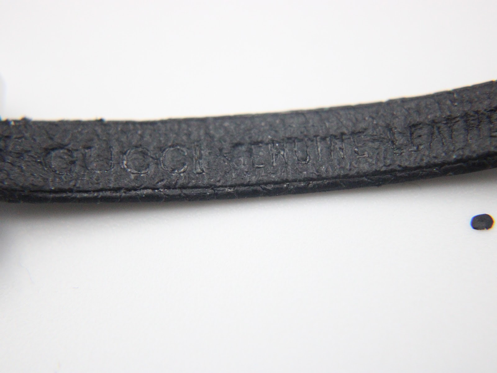 Close-up of the black leather strap, showing 'Gucci genuine leather' embossed text.