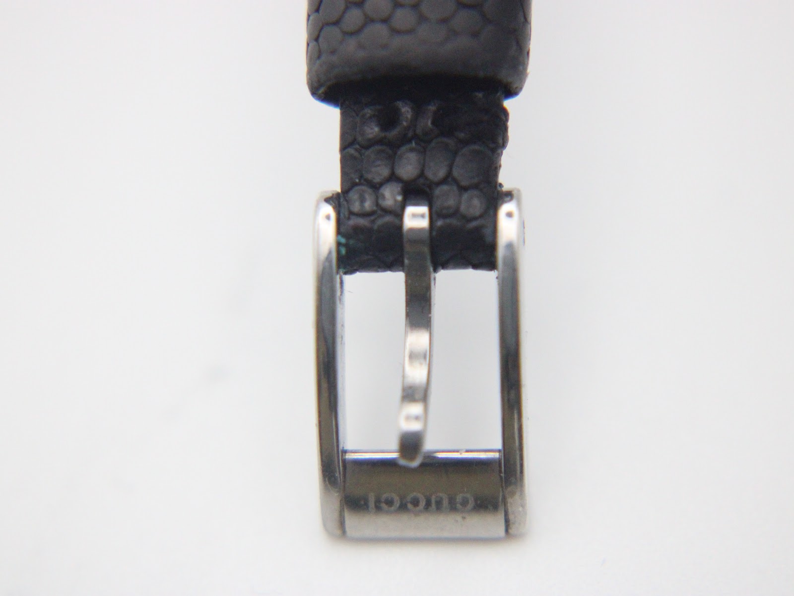 Close-up of the polished stainless steel buckle, clearly engraved with 'Gucci' text.