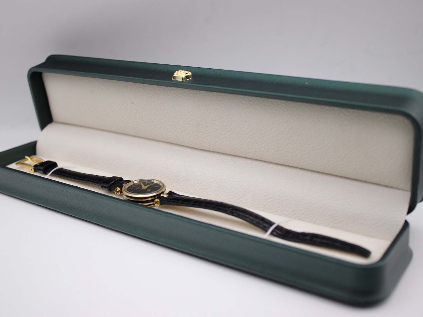 Gucci 2000L watch with black leather strap displayed inside an open green presentation box.