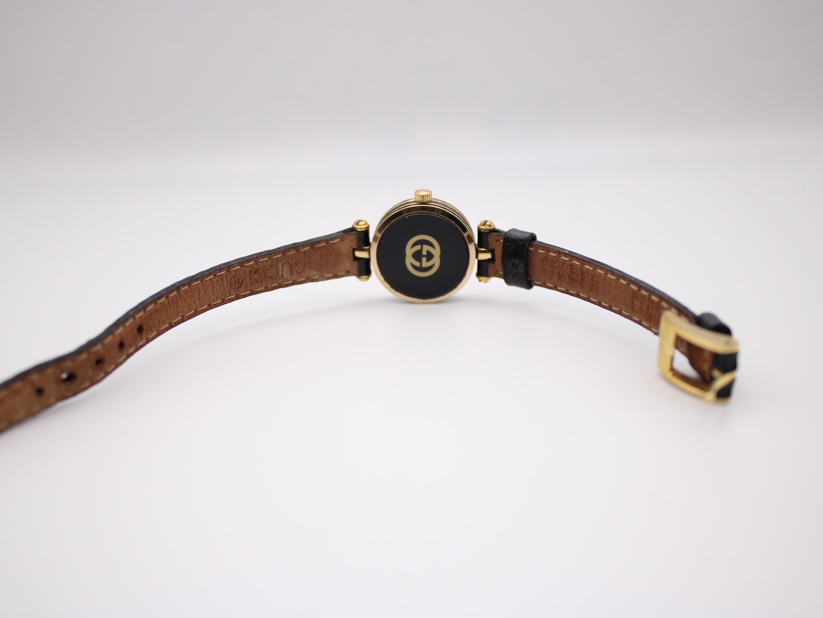 Back view of the Gucci 2000L watch, showing the case back with interlocking G logo and the brown underside of the leather strap.