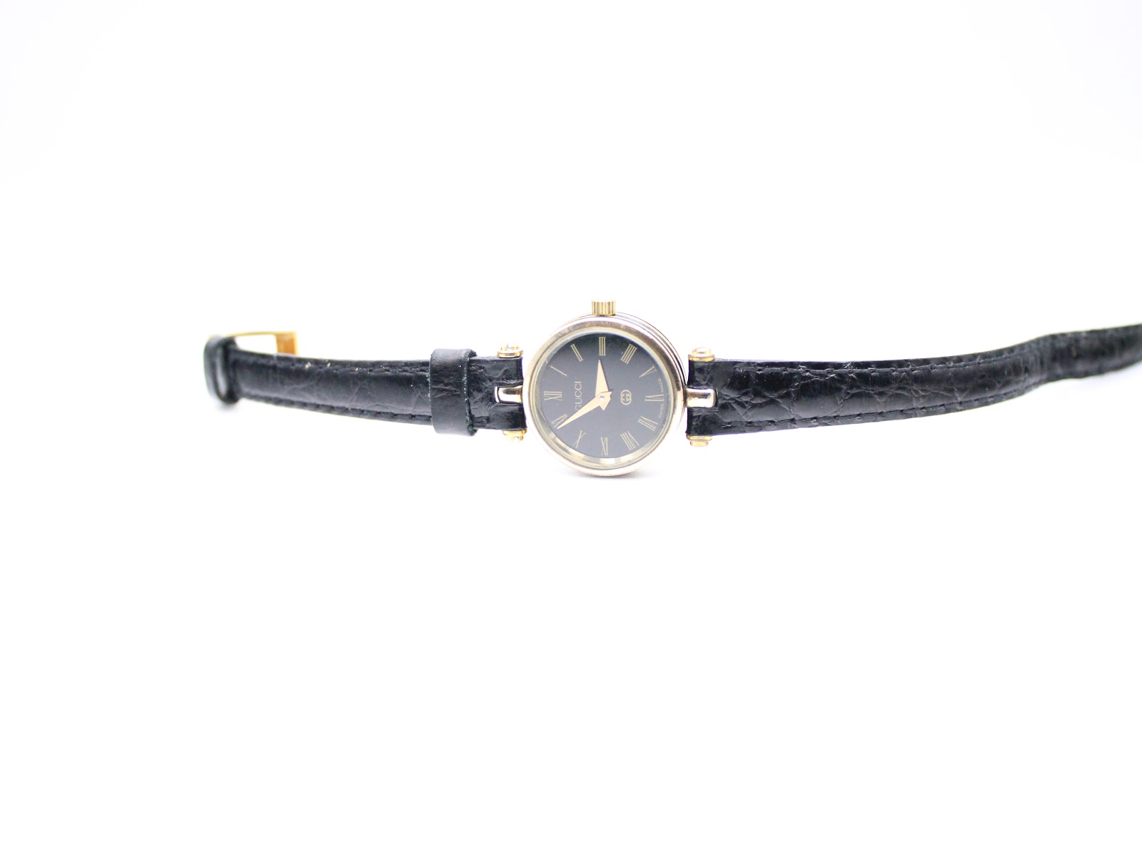 Top-down view of the Gucci 2000L watch with black leather strap fully extended on a white background.