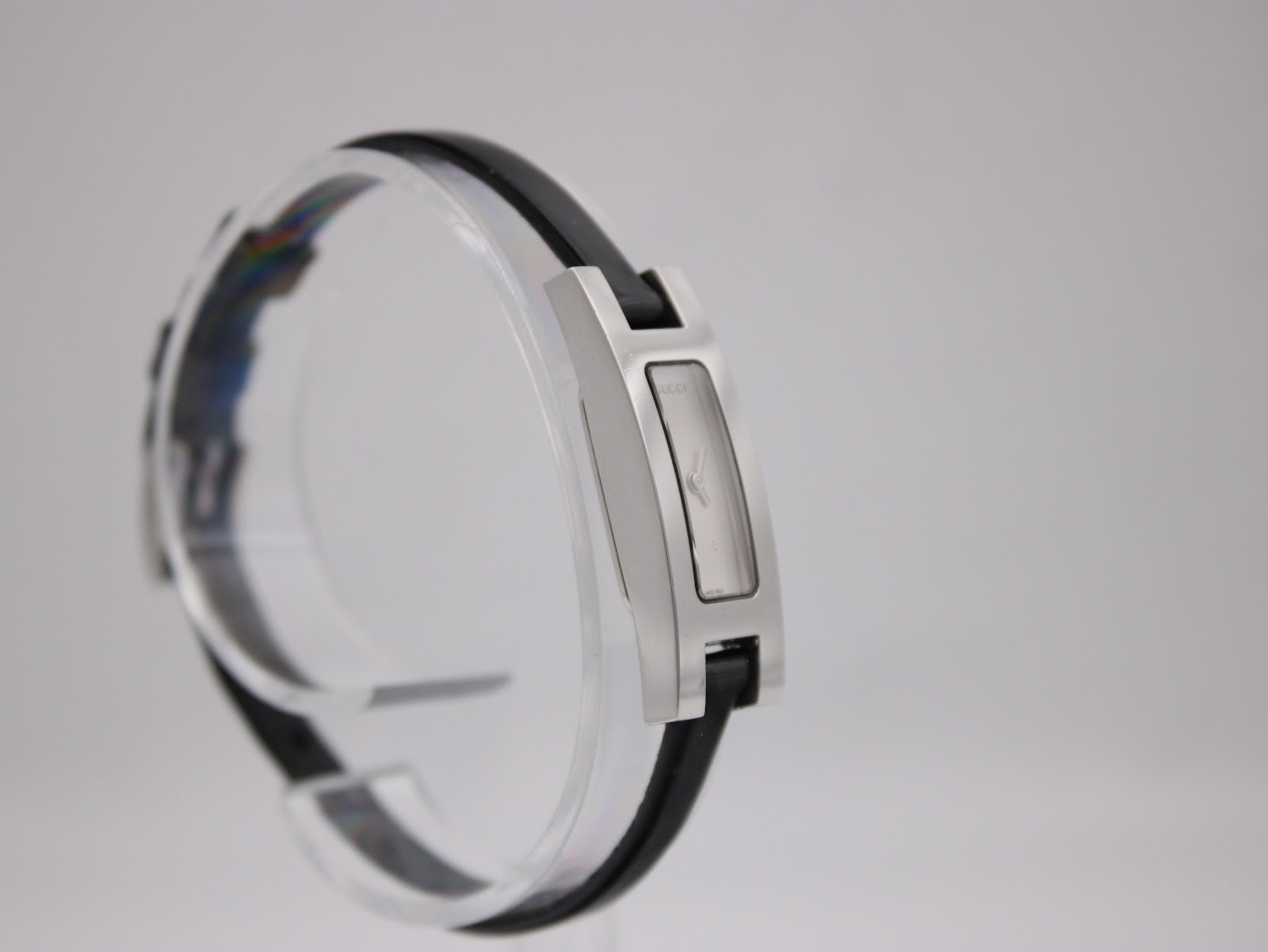 Another side-angled view of the Gucci 3900L on a clear stand, showing the other side of the rectangular case and the black leather strap.