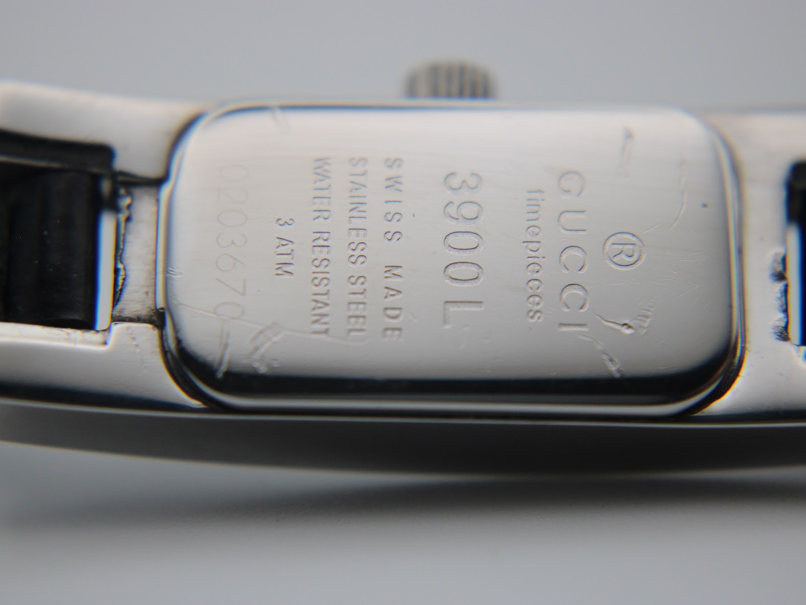 Close-up of the stainless steel case back, showing "Gucci timepieces", "Swiss Made", "Stainless Steel", "Water Resistant 3 ATM", "3900L", and serial number "0203670".