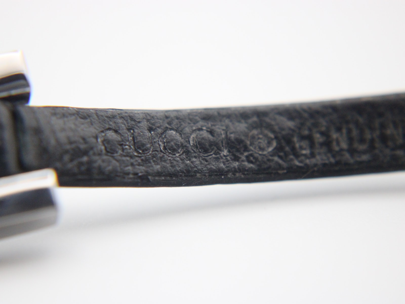Close-up of the black leather strap showing the debossed "GUCCI" stamp.