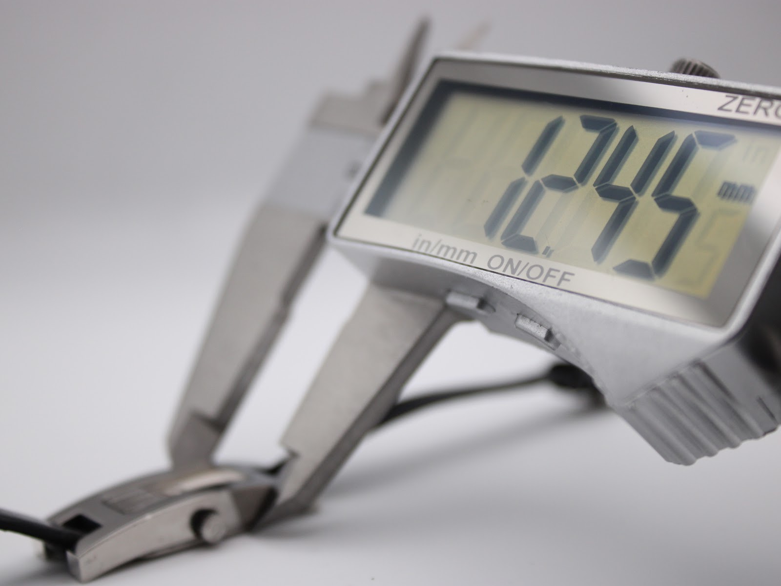 Digital caliper measuring the case width of the Gucci 3900L, displaying a precise reading of 12.45 mm.