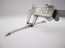 Digital caliper measuring the case diameter of the Gucci G-Frame watch, showing a precise measurement of 14.03 mm.