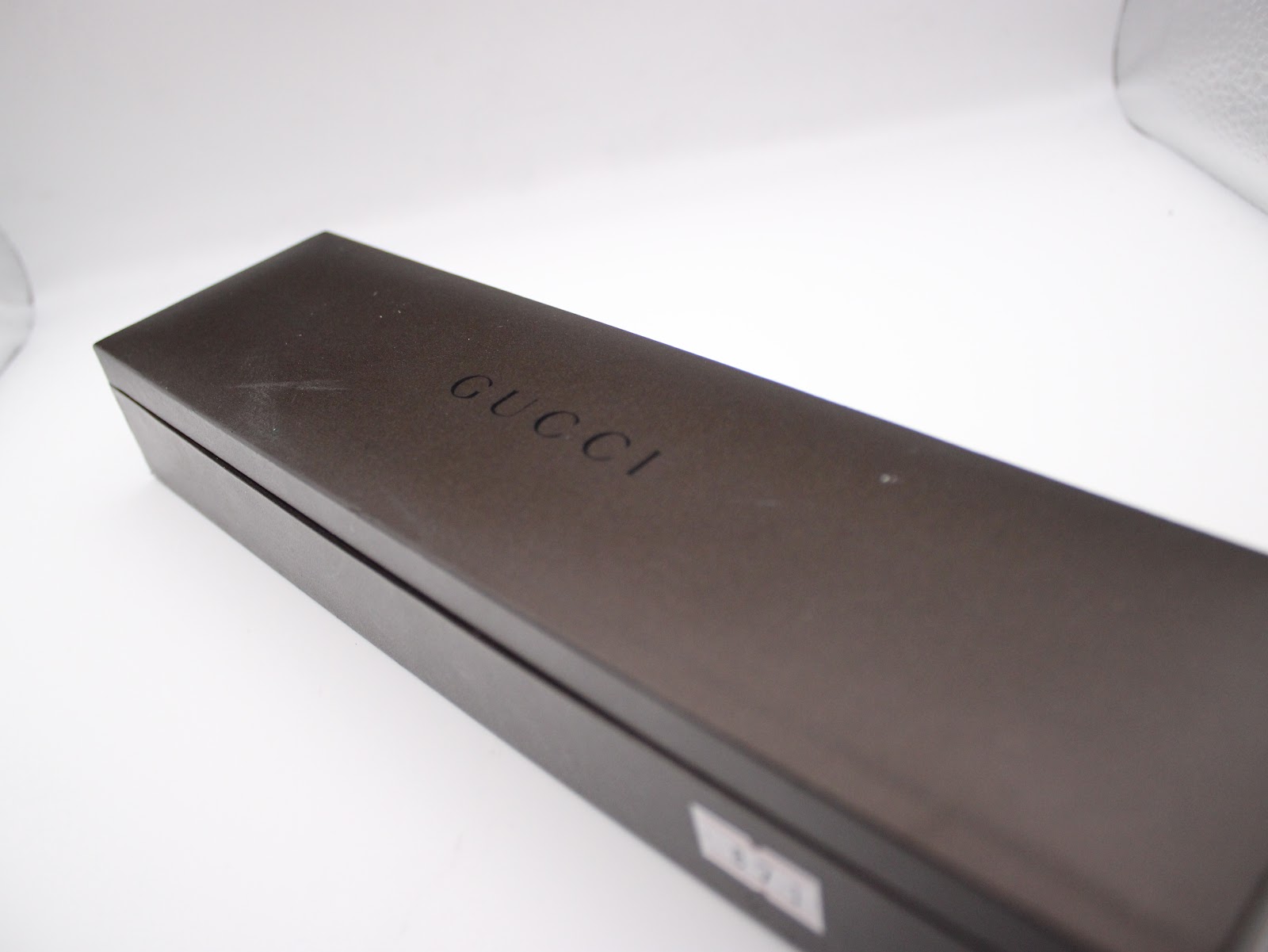 Exterior view of the original dark brown Gucci presentation box with the Gucci logo embossed on the lid.