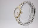 Side-angle view of the Roamer watch on a clear stand, showing the two-tone bracelet and the gold-tone crown with the Roamer 'R' logo.