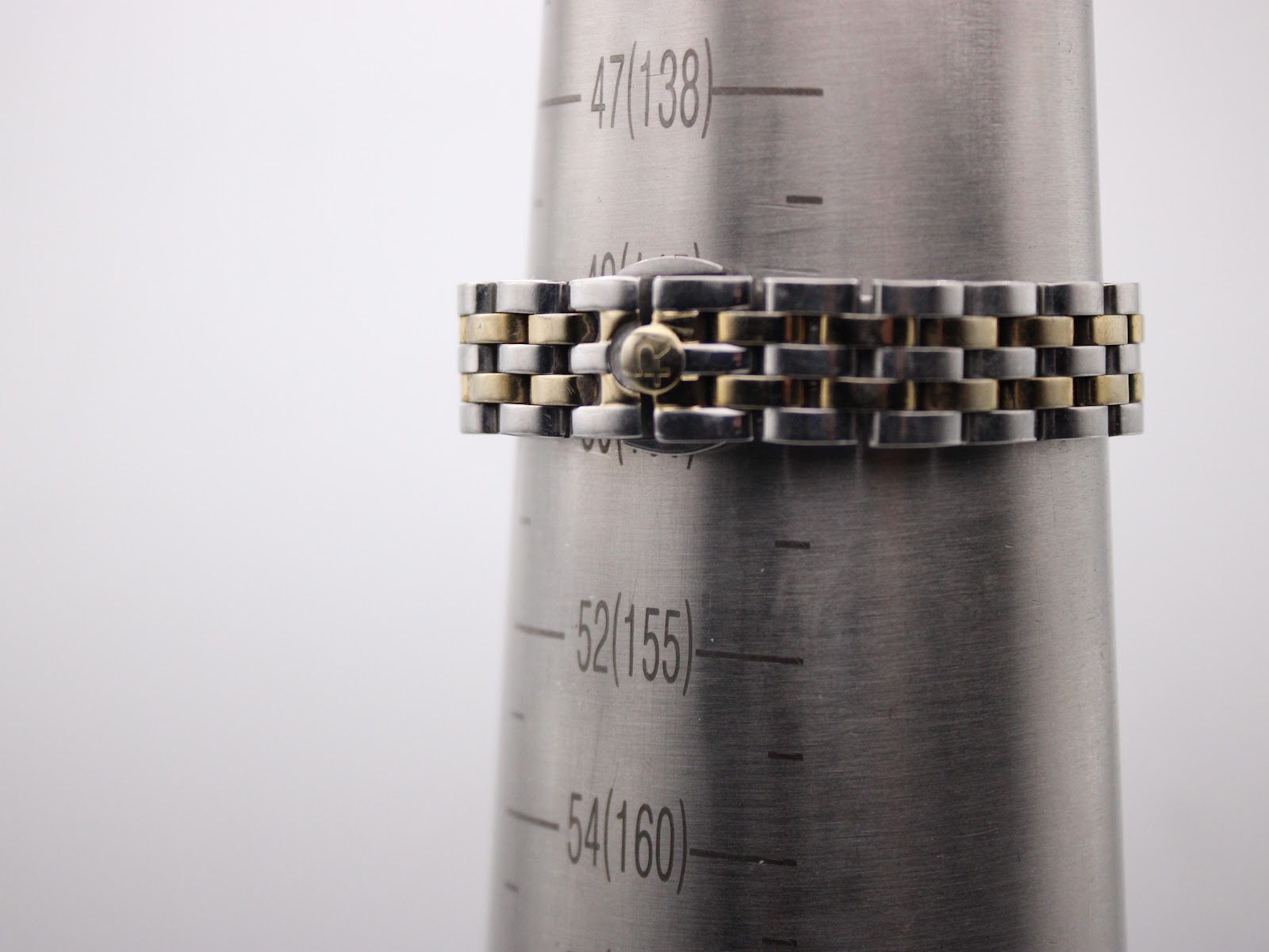 The watch bracelet displayed on a metal wrist sizing gauge, indicating a wrist circumference fit of approximately 155mm.