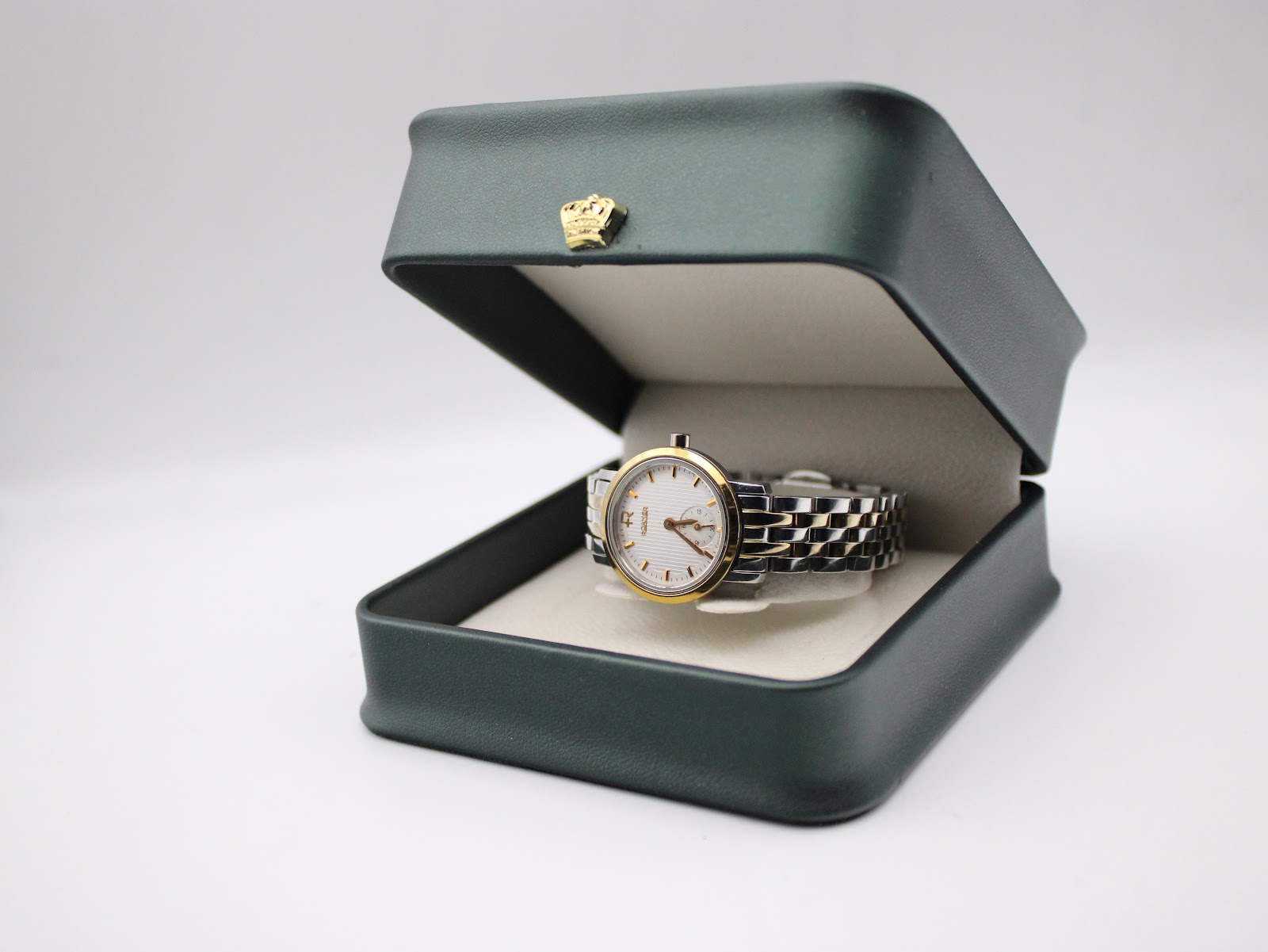 The Roamer watch positioned inside a dark green presentation box with a small gold crown emblem on the lid.