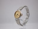 Angled side view of the Dunhill watch on a clear stand, showing gold bezel and two-tone bracelet.