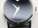 Extreme close-up of the black museum dial, showing the iconic silver dot at 12 o'clock and subtle 'swiss movado quartz' text at 6 o'clock.