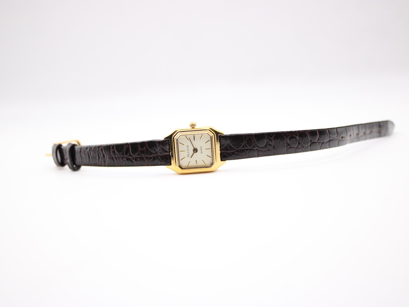 Top-down view of the Bulova watch with its dark brown leather strap laid flat, showing the gold-tone buckle.