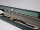 The Bulova watch resting inside an open dark green presentation watch box with a light cream interior.