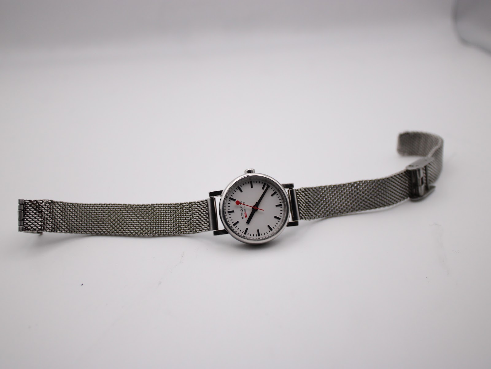 Full view of the Mondaine watch with stainless steel Milanese mesh bracelet laid out flat.