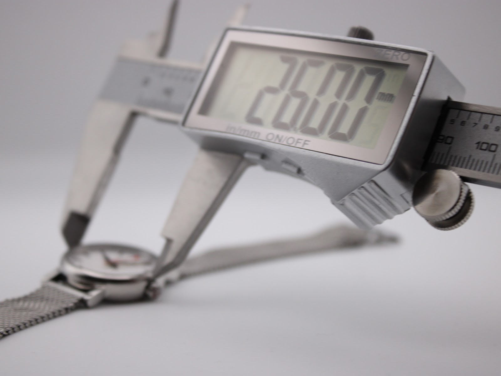 Digital caliper measuring the watch case, displaying a precise diameter of 26.00mm.