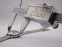 Digital caliper measuring the watch case, displaying a precise diameter of 26.00mm.
