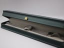 Mondaine watch with mesh bracelet displayed inside a dark green presentation box.