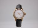 Front view of Tissot T085210A ladies' quartz watch with gold-tone case, silver dial, and dark brown leather strap on display stand.