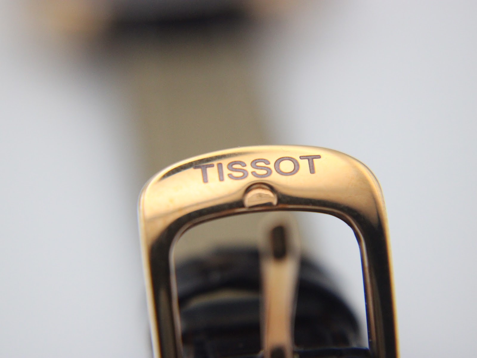 Close-up of the gold-tone buckle, clearly showing the embossed "TISSOT" logo.