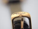 Close-up of the gold-tone buckle, clearly showing the embossed "TISSOT" logo.