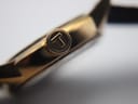 Macro shot of the gold-tone crown with the Tissot 'T' logo engraved on its end.