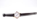 Full length view of the Tissot watch laid flat with the dark brown leather strap extended.