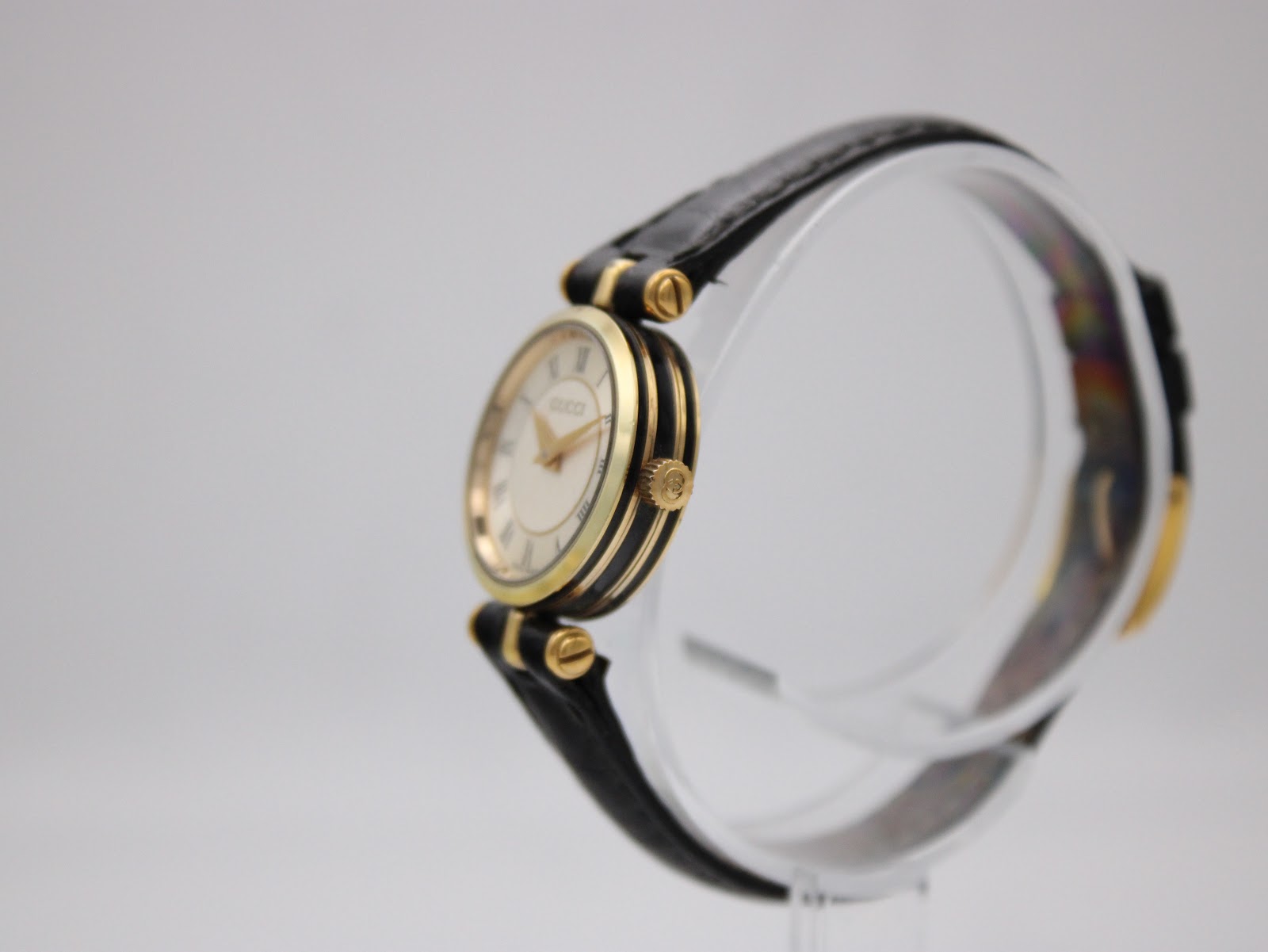 Right side profile of the Gucci 2000L watch, highlighting the gold-tone case, black side detailing, and signed Gucci crown.