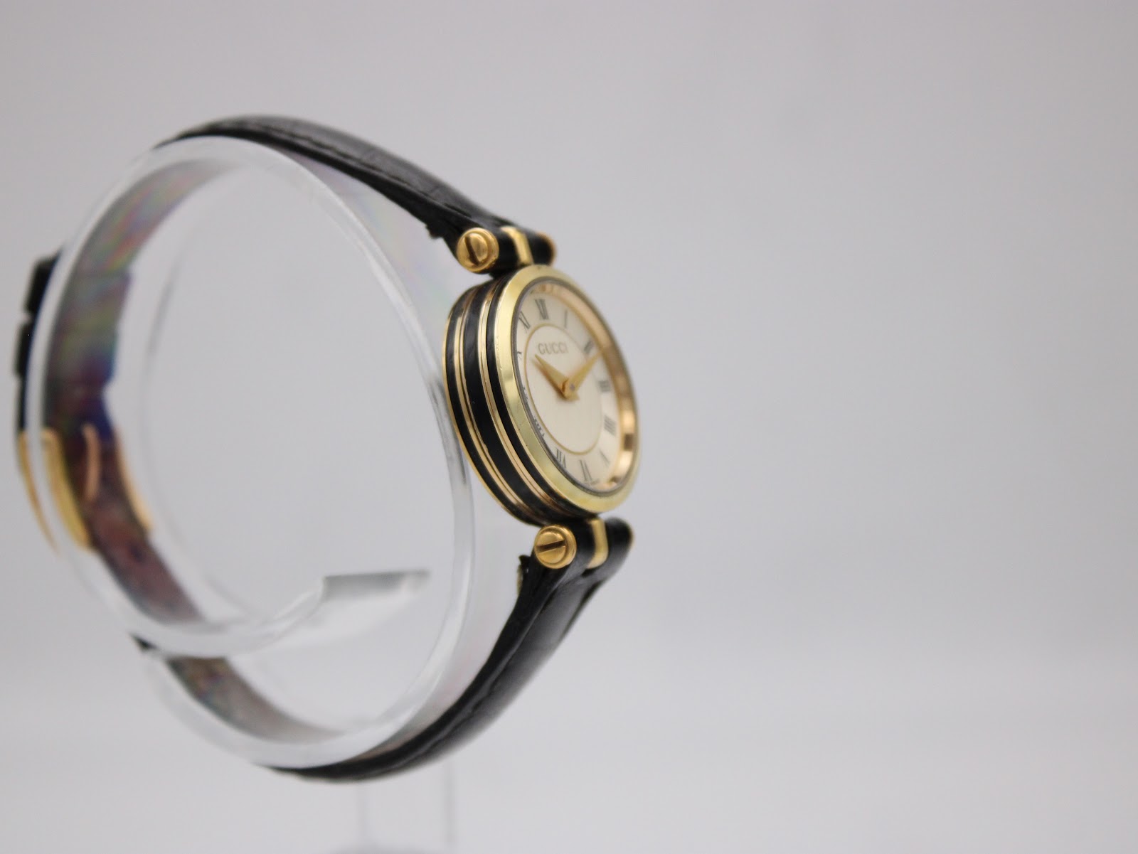 Left side profile of the Gucci 2000L watch, showcasing the gold-tone case and the elegant lines of the watch.