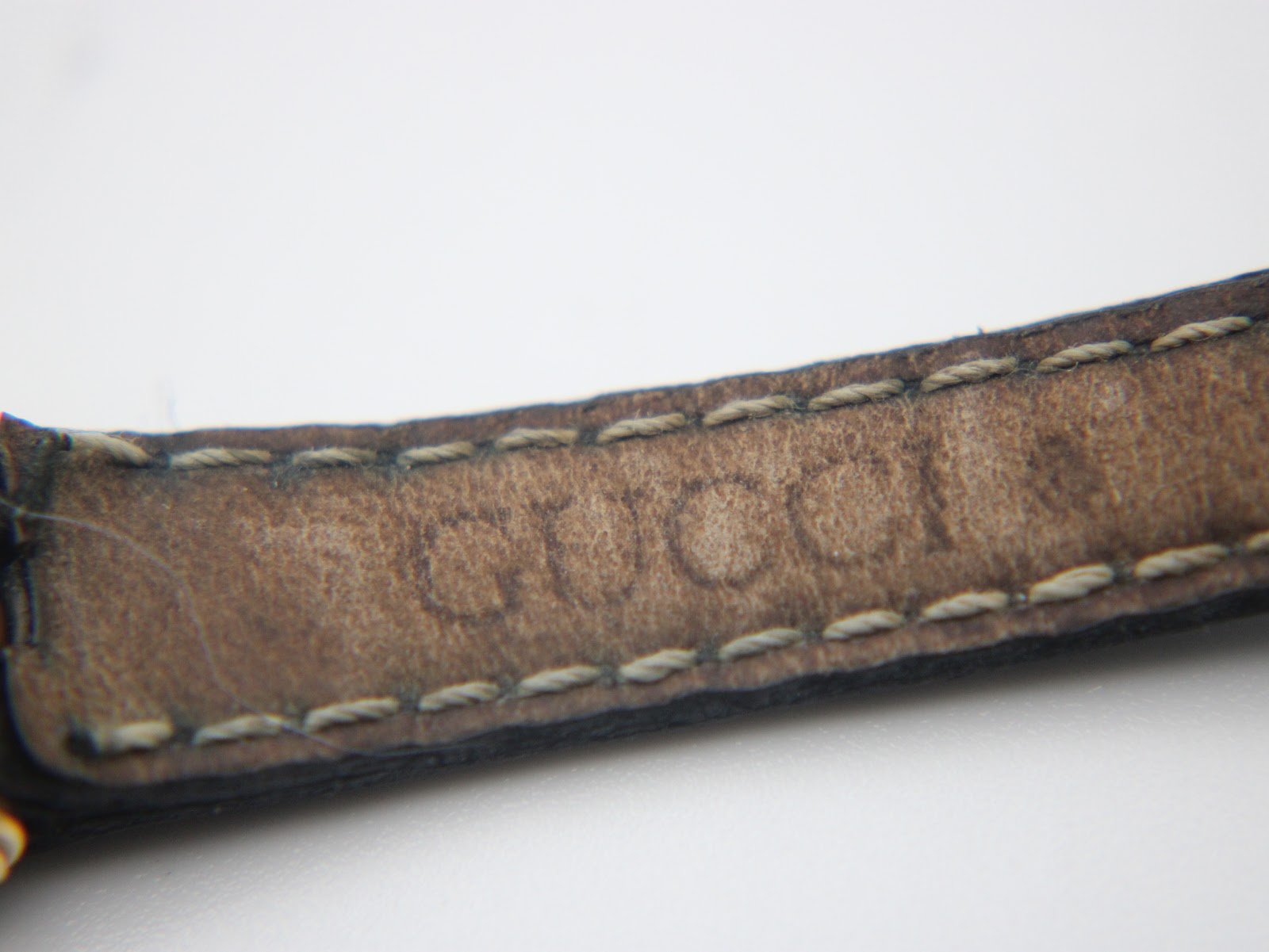 Close-up of the inside of the black leather strap, showing the embossed 'GUCCI' branding.