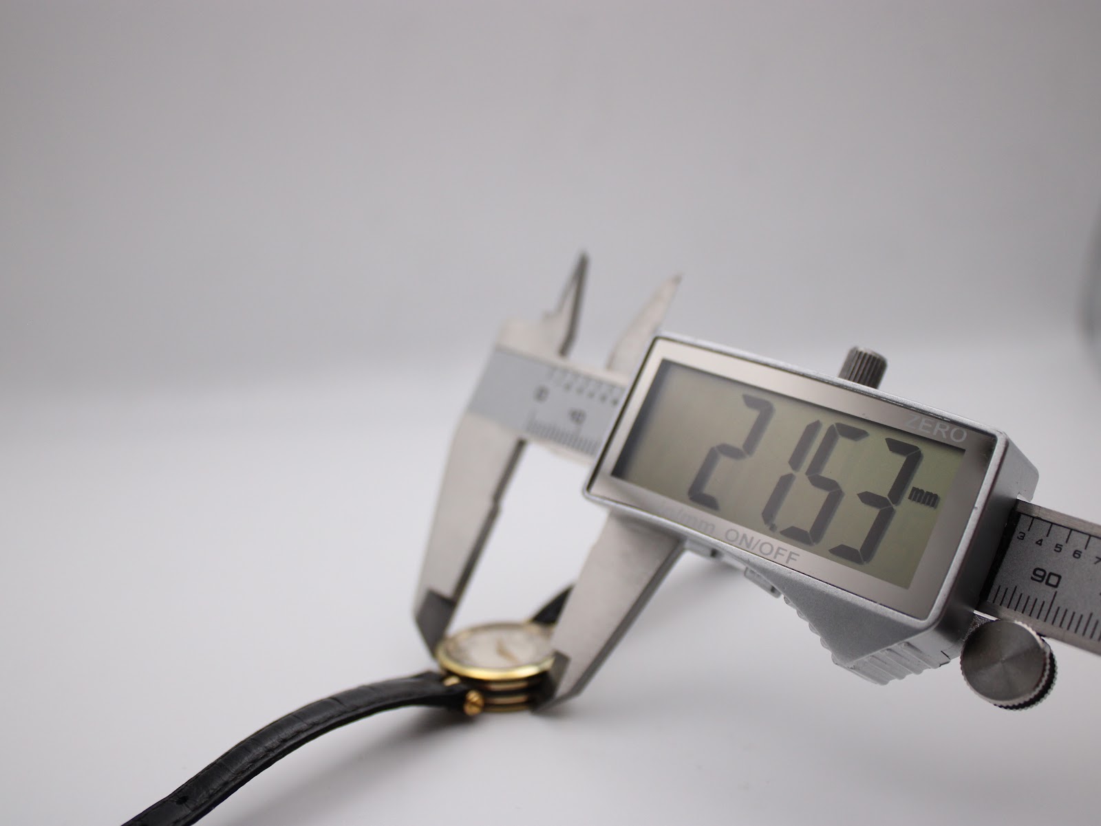 Digital caliper measuring the case diameter of the Gucci 2000L watch at 21.53mm, showing precision measurement.