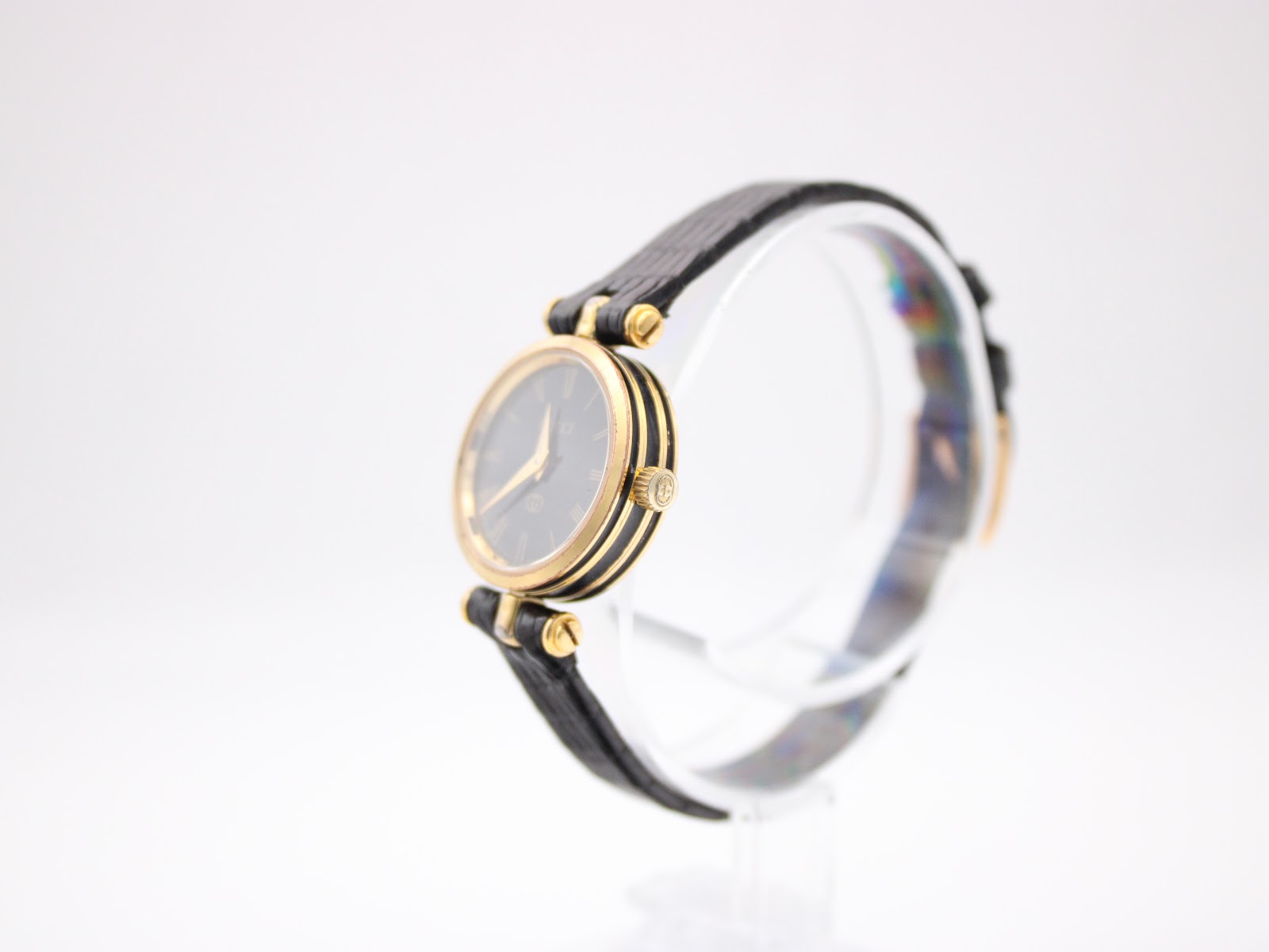 Angled side view of the Gucci 2000L watch on a stand, highlighting the slim gold-plated case and original crown.