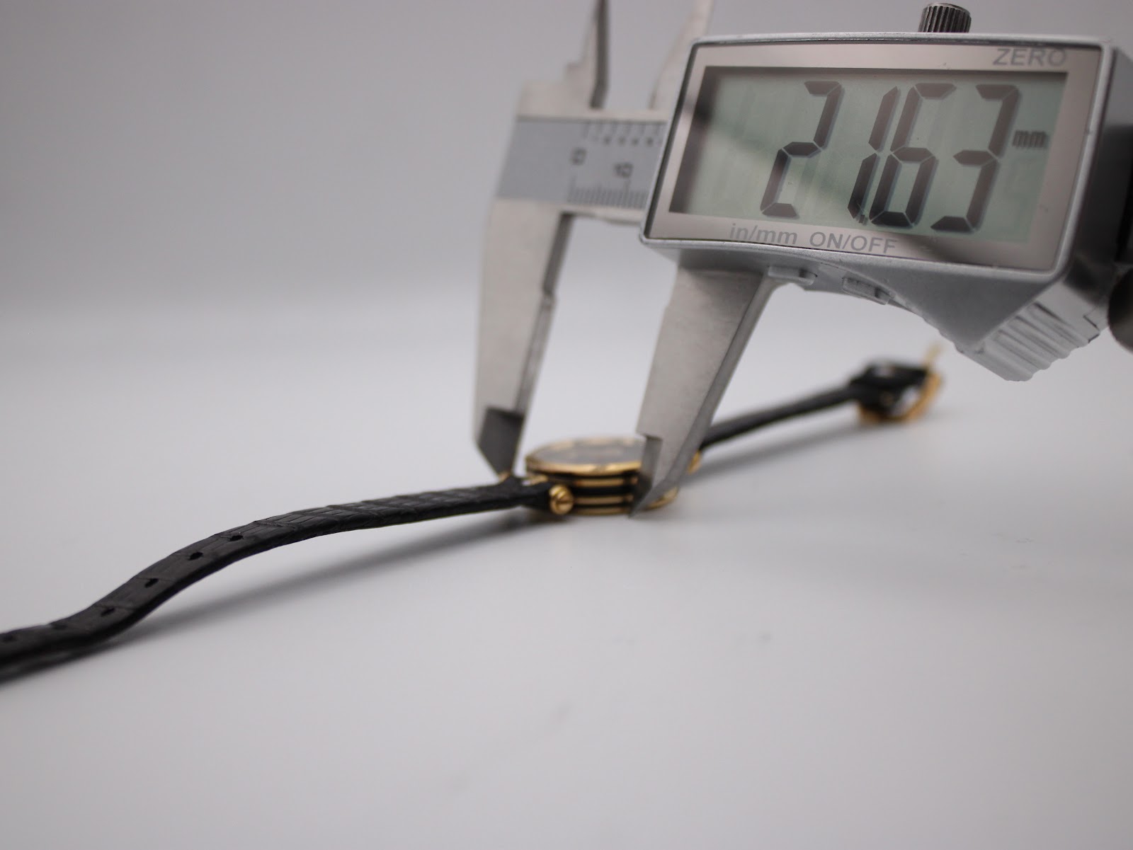 Digital caliper measuring the case diameter of the watch, displaying 21.63 mm.
