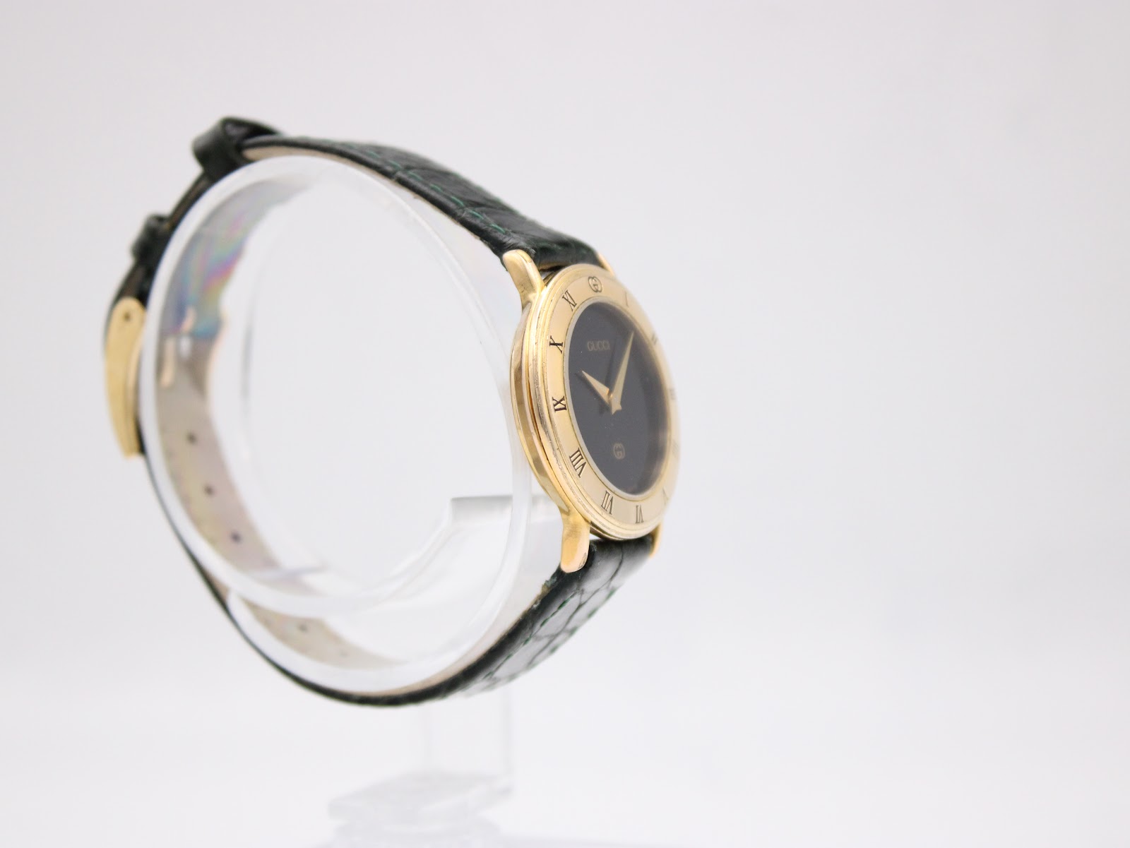 Close-up detail of the dark green leather strap and signed Gucci gold-tone buckle.