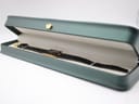 The Raymond Weil Othello watch resting inside a dark green presentation box with a cream interior