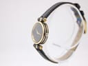 Side view of the Gucci 2000L watch on a stand, highlighting the slim profile and gold-plated case and original crown.