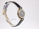 Angled side view of the Gucci 2000L watch, showing the black dial and gold case detail on a clear stand.