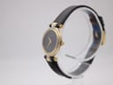 Angled side view of the Gucci 4500L watch showing the two-tone case, gold-tone crown, and black leather strap.
