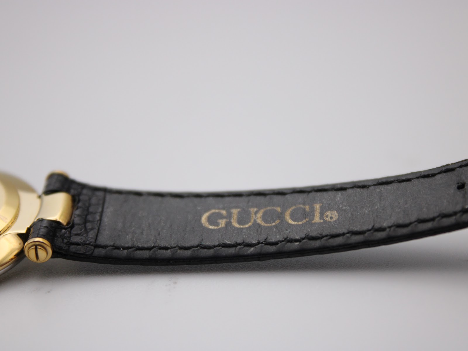 Close-up of the black leather strap interior, showing the embossed 'GUCCI®' logo.
