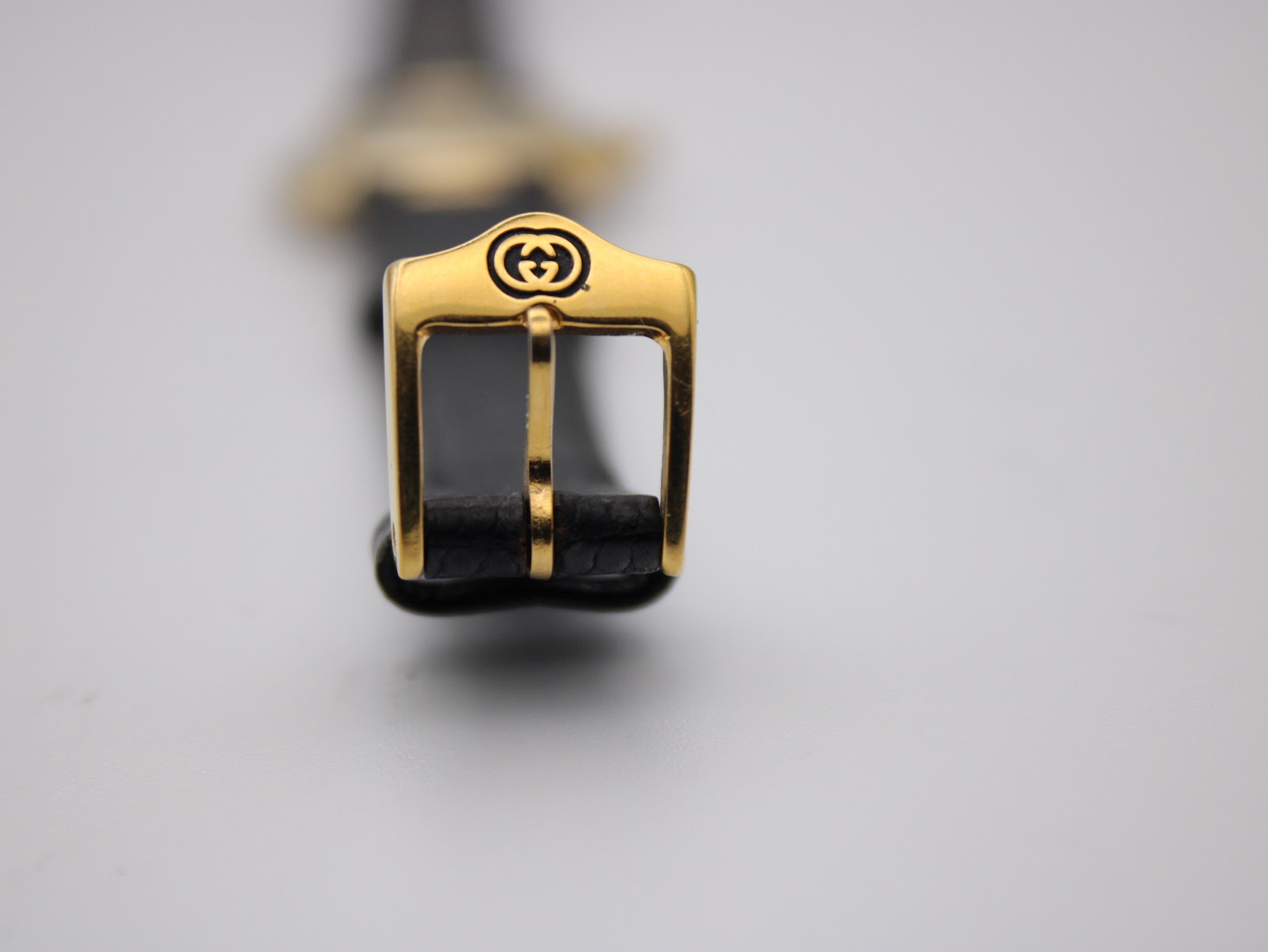 Close-up of the gold-tone buckle, featuring the iconic interlocking Gucci G logo.