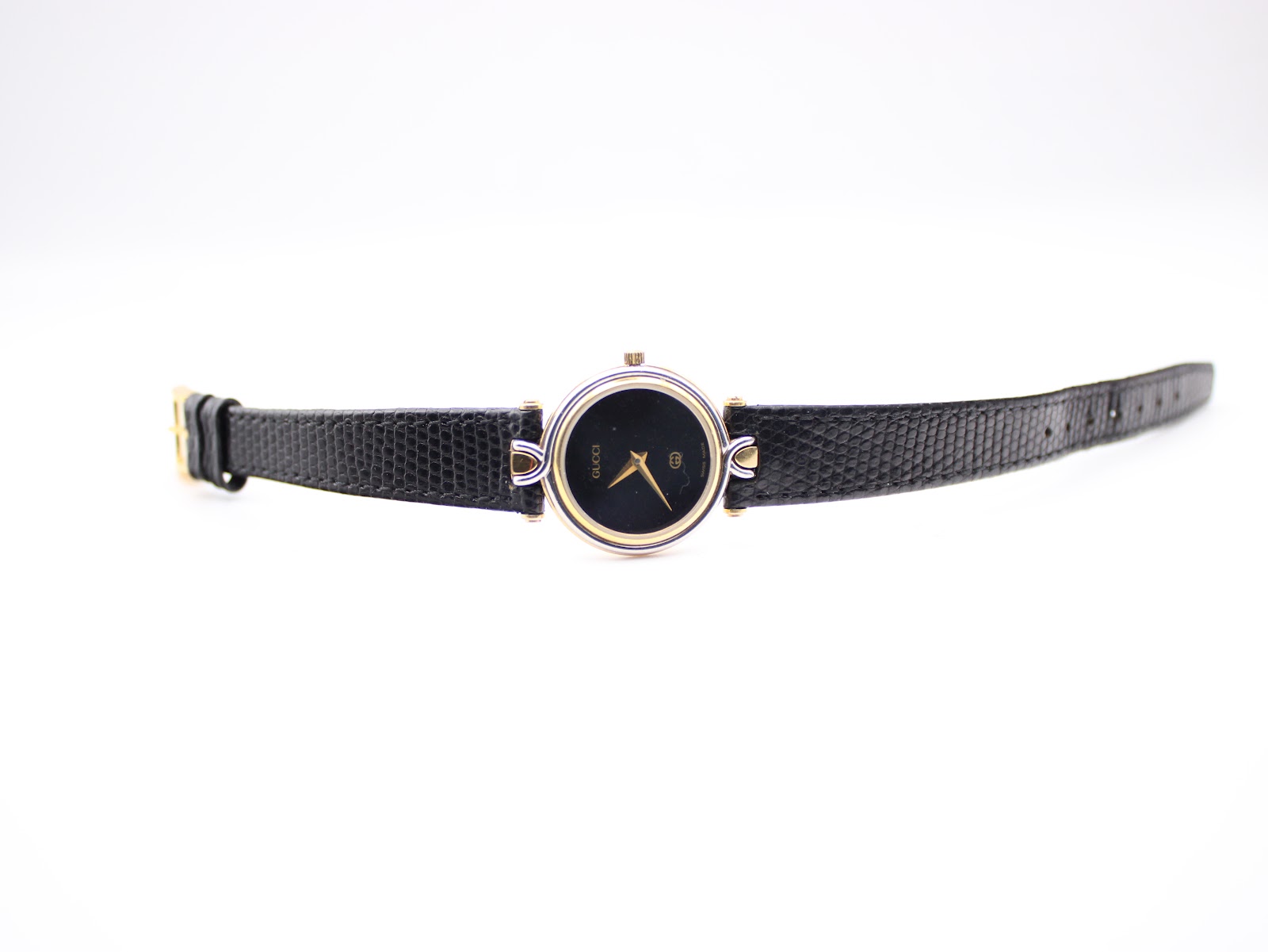 Full length view of the Gucci 4500L watch with its black leather strap laid flat on a white surface.