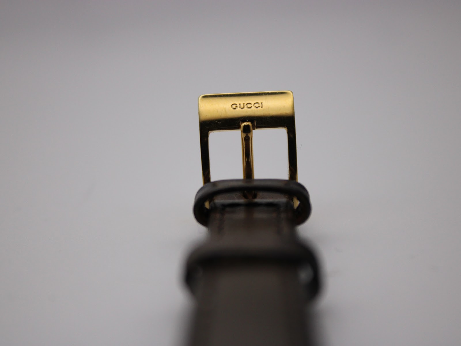 Close-up of the gold-tone buckle, clearly displaying the 'GUCCI' signature.