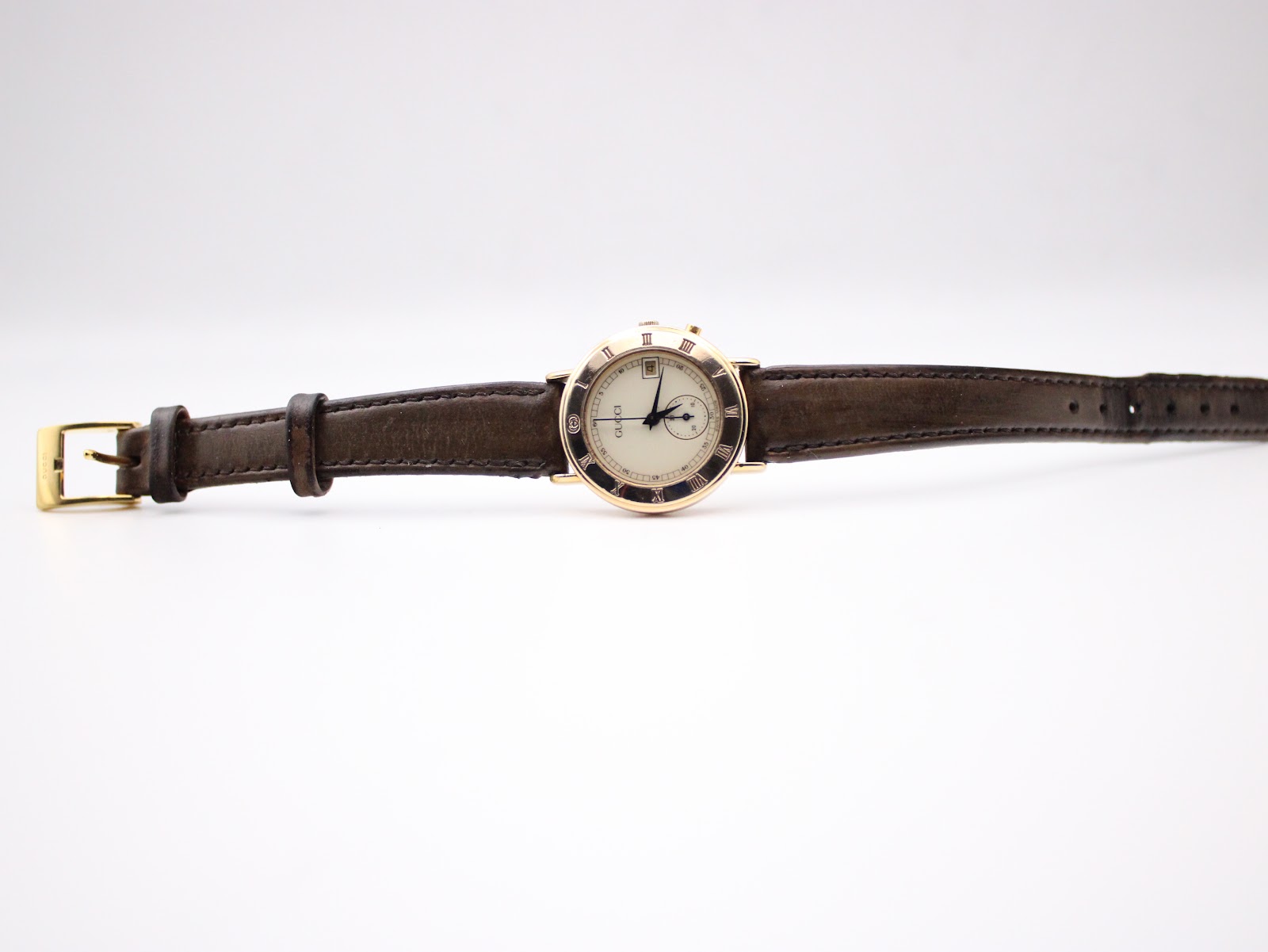 Full front view of the Gucci 3800L watch with the brown leather strap fully extended, showing the dial and signed buckle.