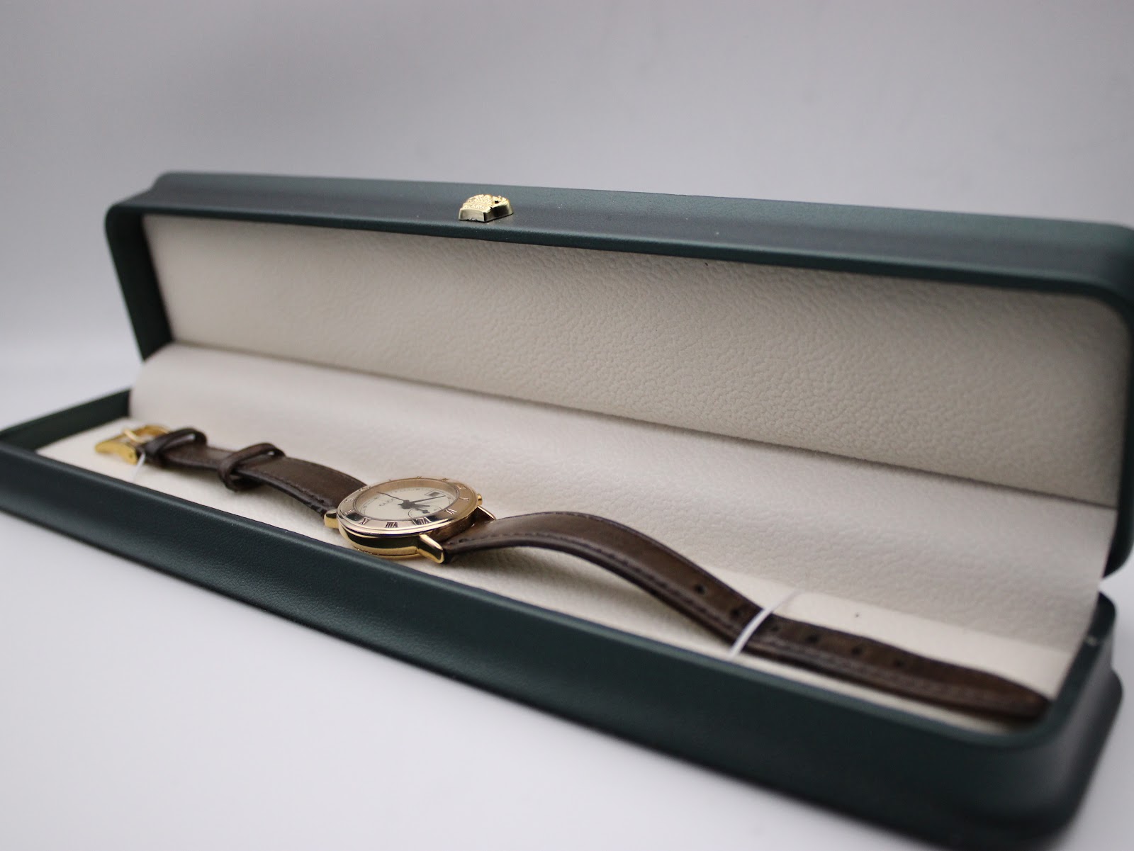 The Gucci 3800L watch resting within an open green presentation box on a white background.
