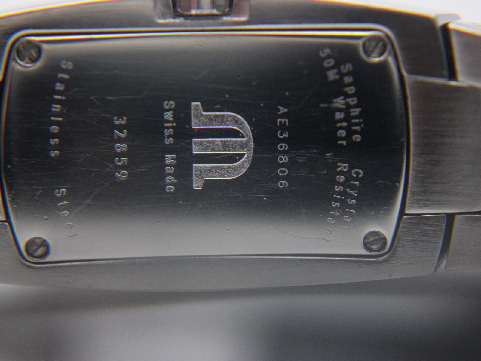 Close-up of the watch's stainless steel case back, engraved with "Maurice Lacroix Swiss Made 32859", "Sapphire Crystal", and "50M Water Resistant".